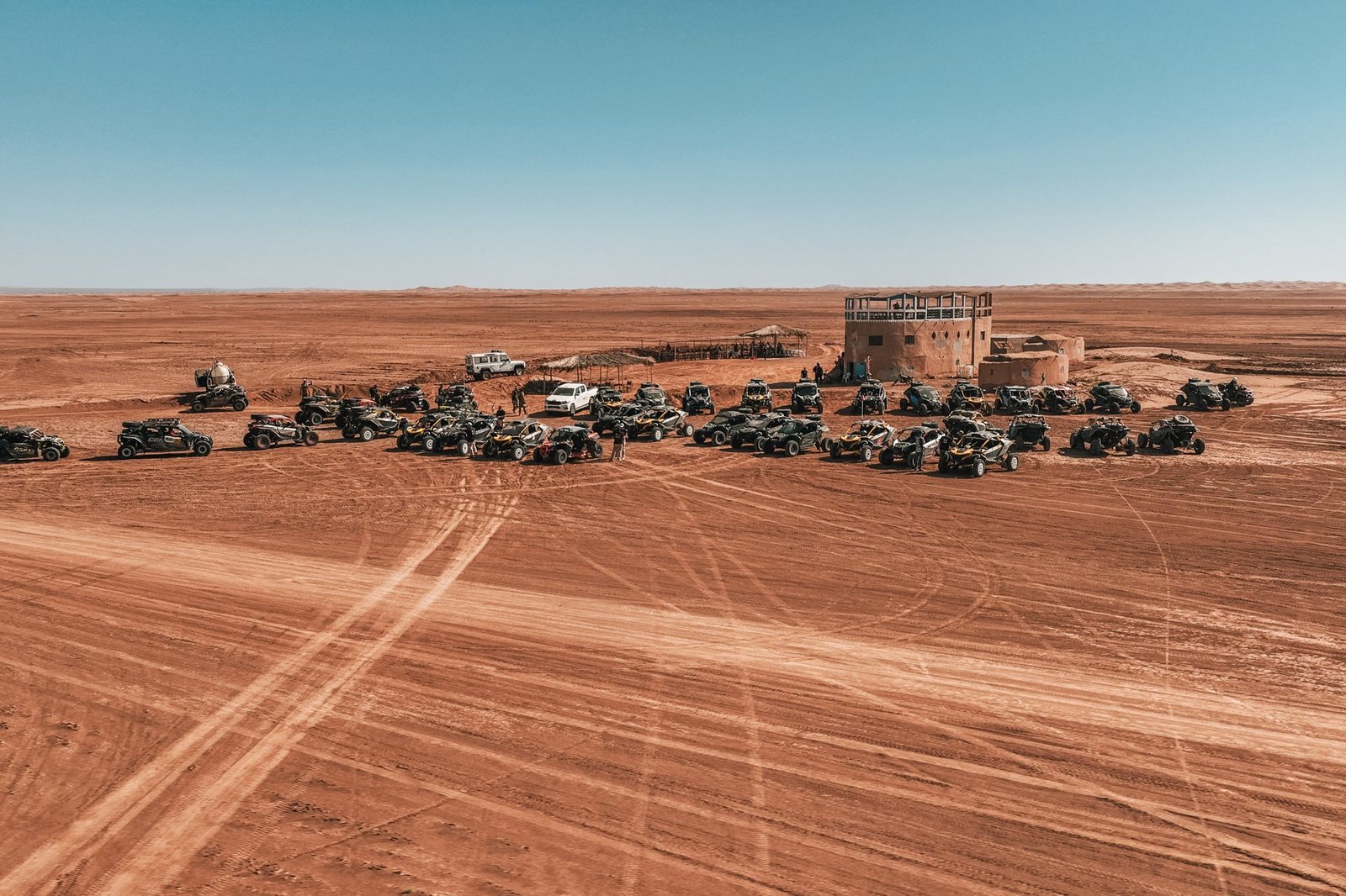 Convoi de SSV Can-Am regroupé dans le reg marocain devant une kasbah, vue aérienne par drone, Raid Can-Am Spirit 2026